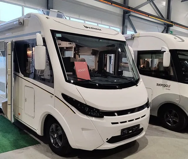 Bobil av merket Dethleffs med "SOLGT"-skilt i frontruten, parkert i lys utstillingshall.