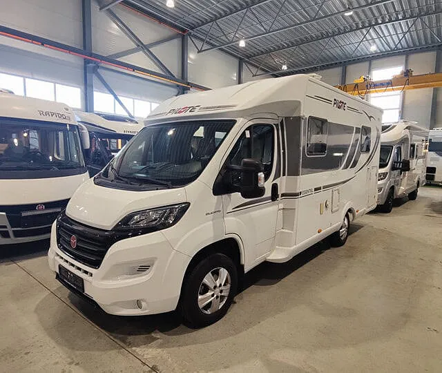 Pilot-bobil i hvitt og grått vist i utstillingshall sammen med flere bobiler av ulike merker.